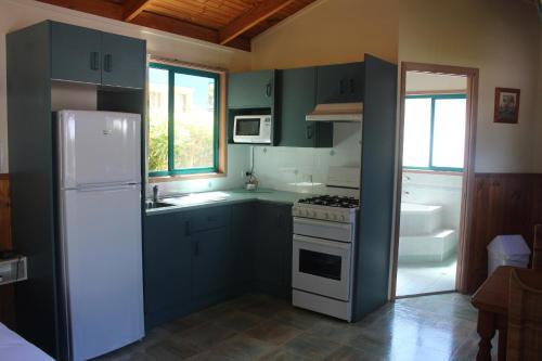 a kitchen with green cabinets and a white refrigerator at Lani's Holiday Island in Forster