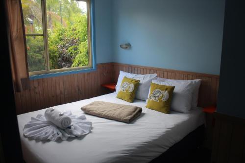 a bed with towels and pillows on it with a window at Lani's Holiday Island in Forster