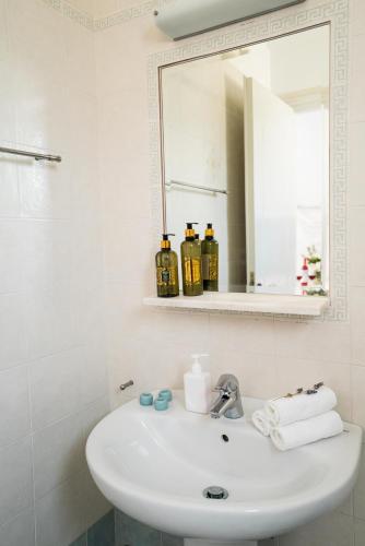 a white bathroom with a sink and a mirror at Plori Studios and Apartments in Aegiali