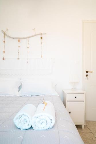 a bedroom with a white bed with towels on it at Plori Studios and Apartments in Aegiali