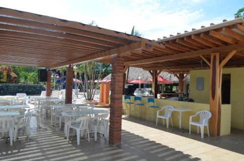 a restaurant with tables and chairs under a wooden roof at Hosteria Guaracú in San Jerónimo