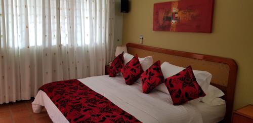 a bedroom with a bed with red and white pillows at Hosteria Guaracú in San Jerónimo