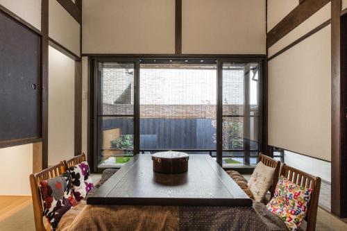 une salle à manger avec une table et une grande fenêtre dans l'établissement 京町家一棟貸しKyoto Machiya Stay En, à Kyoto