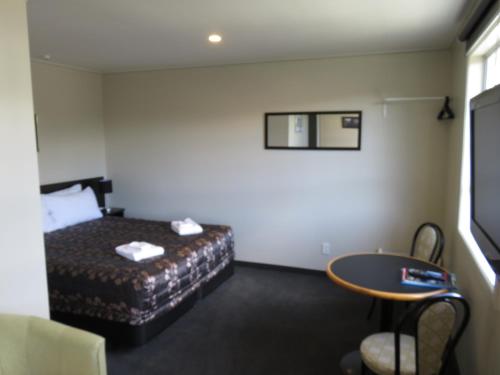 a hotel room with a bed and a table at Admirals Motor Lodge in Blenheim