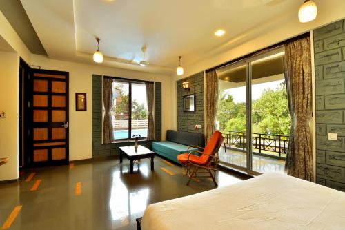 ein Schlafzimmer mit einem Bett, einem Sofa und einem Tisch in der Unterkunft The Mango Inn in Dapoli
