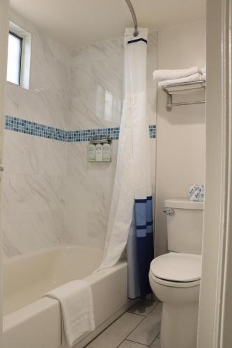 a white bathroom with a tub and a toilet at University Inn in Tucson