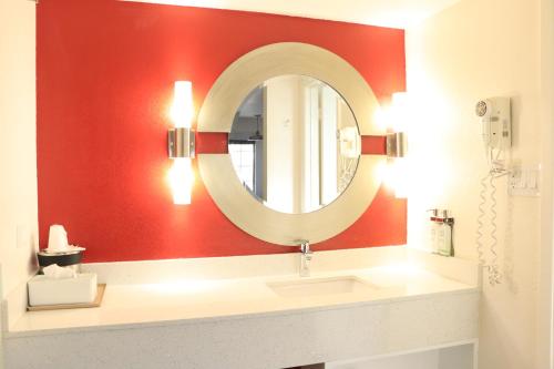 a bathroom with a mirror on a red wall at University Inn in Tucson