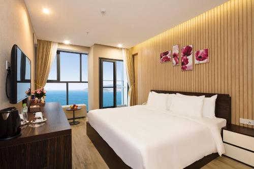 a hotel room with a large white bed and a window at Emerald Bay Hotel & Spa Nha Trang in Nha Trang