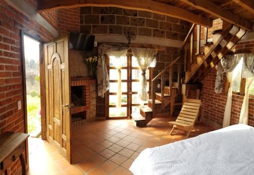 een slaapkamer met een bed en een bakstenen muur bij Cabañas villa de San Miguel in Huasca de Ocampo
