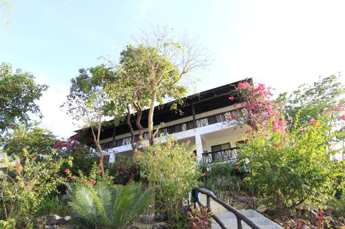 a building with trees and flowers in front of it at Discovery Island Resort in Coron