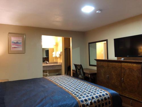a hotel room with a bed and a flat screen tv at Villa West Inn in Odessa