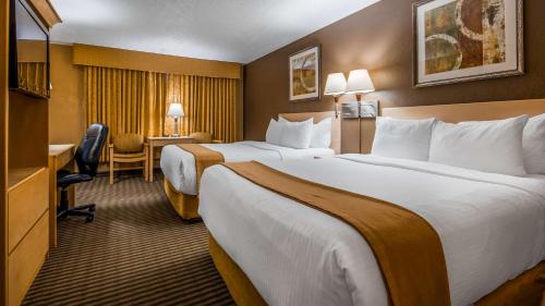 a hotel room with two beds and a desk at Seven Oaks Hotel Regina in Regina