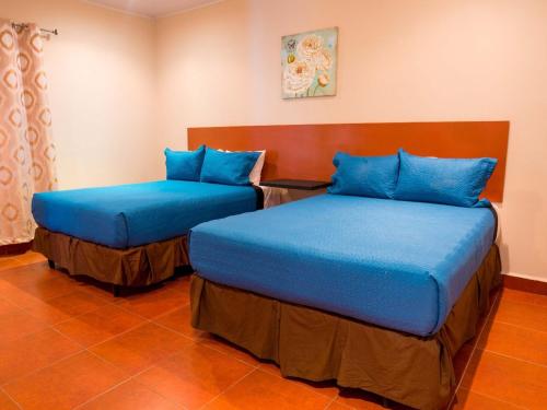 2 letti in una camera con cuscini blu di HM HOTEL a Choluteca