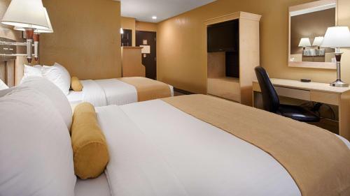 a hotel room with two beds and a desk at Seven Oaks Hotel Regina in Regina