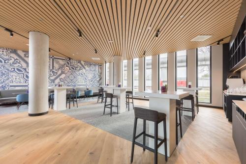 a dining room with tables and chairs and windows at Postillion Hotel Amsterdam in Amsterdam