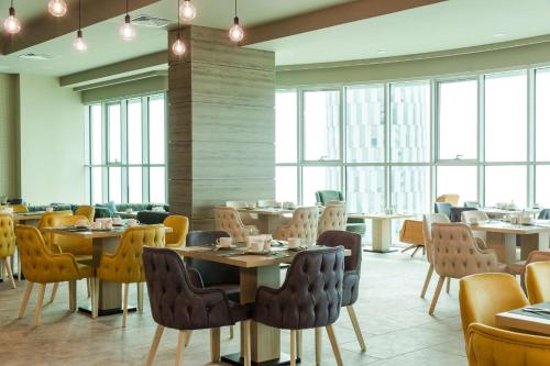 a dining room with tables and chairs and windows at Best Western Premier Batumi in Batumi