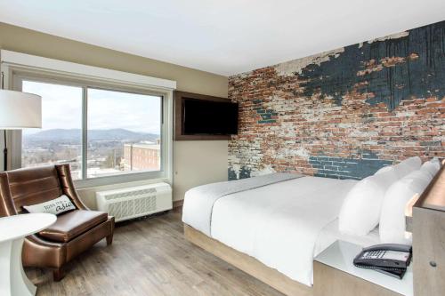 a bedroom with a brick wall and a bed and a chair at Cambria Hotel Downtown Asheville in Asheville