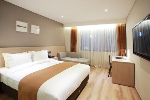 a hotel room with a large bed and a chair at Gangneung City Hotel in Gangneung