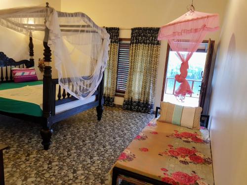 a bedroom with a canopy bed and a window at Pearl Cave Cabanas & Resturant in Tangalle