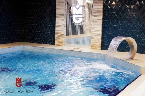 タシュケントにあるグランド ミール ホテルのバスルーム(水の蛇口付)が備わるスイミングプール