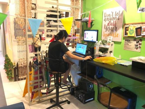 a woman sitting at a counter with a laptop computer at Woodpecker Lodge, Kuching in Kuching