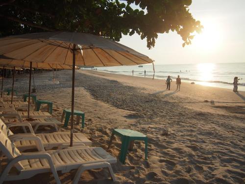 a beach with chairs and an umbrella and people on the beach at Nong Nuey Rooms in Ko Samed