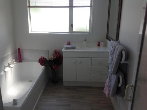 a bathroom with a tub and a sink and a window at Seaside/Golf B n B in Christchurch