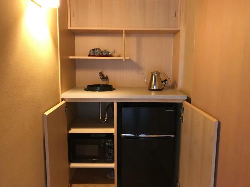 a small kitchen with a counter and a black refrigerator at ShikiShiki Shinra in Kyoto