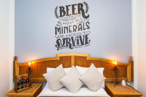 a bedroom with a bed with pillows and a sign on the wall at Mala Vecindad Beer Hotel in Mexico City