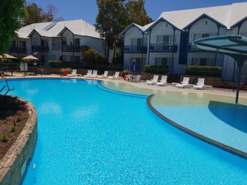 a large blue swimming pool with chairs and condos at Mandurah Quay Resort in Mandurah
