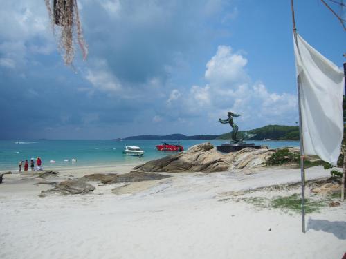 a statue on a beach with people in the water at Nong Nuey Rooms in Ko Samed