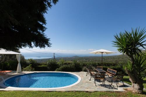 uma piscina com cadeiras, uma mesa e um guarda-sol em Villa Heavens Knights with private pool em Magoúla