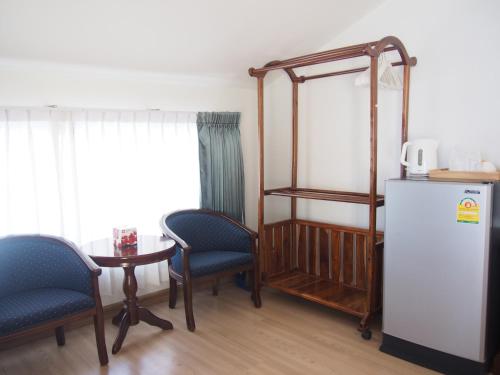 Nong Nuey Rooms في كو ساميد: غرفة فيها ثلاجة وطاولة وكراسي