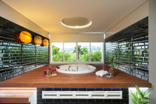 Un baño con bañera y una gran ventana. en Clove Hotel Bandung, en Bandung
