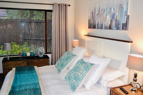 a bedroom with a white bed with pillows and a window at Serendipity Cottage in Johannesburg