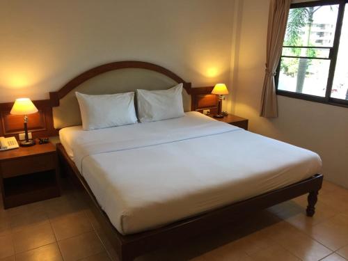 a bedroom with a large white bed with two lamps at PS Hill Resort Phuket Patong - SHA Plus in Patong Beach