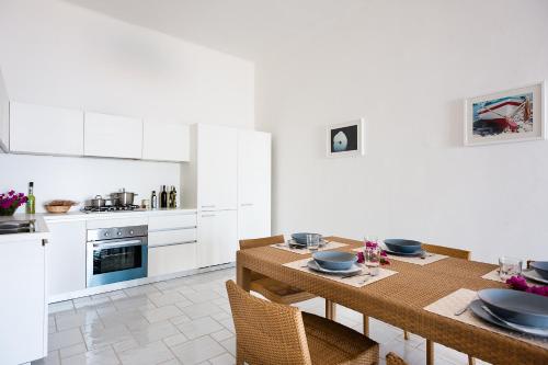 a white kitchen with a wooden table with chairs at NerOssidiana in Acquacalda