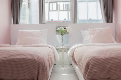 two beds in a white bedroom with a vase of flowers at MJ Stay 2 in Seoul