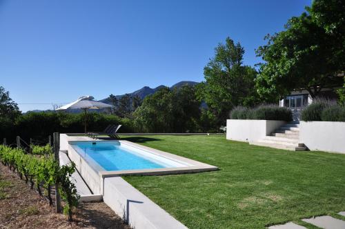 un patio trasero con piscina y césped en Blueberry Hill Cottages en Franschhoek