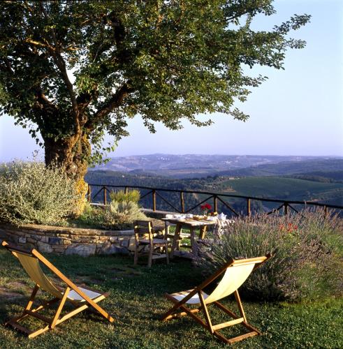 a table and chairs on a hill with a tree at Romitorio di Serelle in Barberino di Val dʼElsa