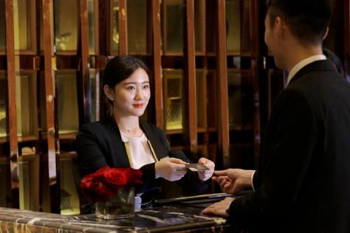 a man handing a woman something in front of a mirror at Dongguan Kande International Hotel in Dongguan