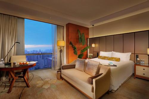 1 dormitorio con cama, silla y escritorio en Dongguan Kande International Hotel, en Dongguan