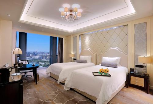 a hotel room with two beds and a chandelier at Dongguan Kande International Hotel in Dongguan