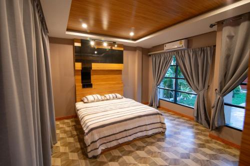 a bedroom with a bed and a large window at GetZleep PoolVilla in Sattahip