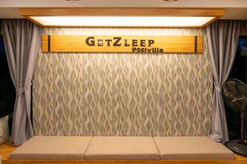 a bed in a room with a sign on the wall at GetZleep PoolVilla in Sattahip