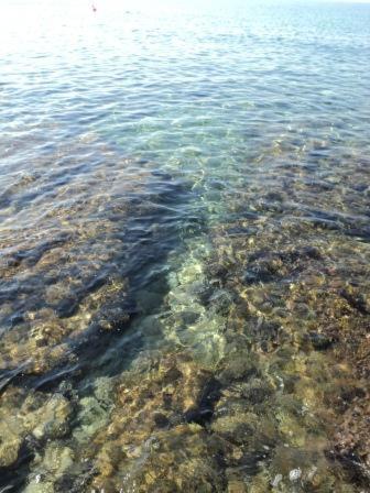 a large body of water with rocks andploadploadploadploadploadploadpload at Casa Direttamente sul mare in Marina di Mancaversa