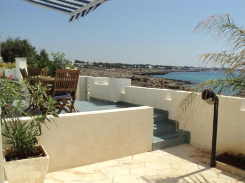 a patio with a table and chairs and the ocean at Casa Direttamente sul mare in Marina di Mancaversa