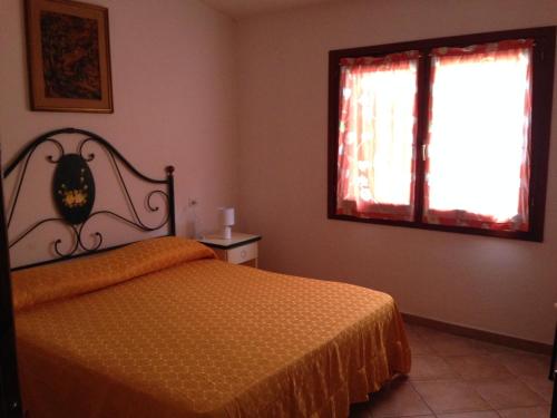1 dormitorio con cama y ventana en Appartamenti Rena Majore, en Aglientu