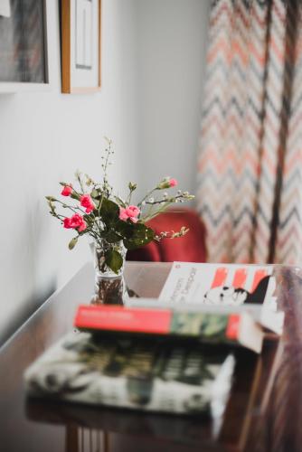 a vase of flowers on a table with a book at Kjobing Manor in Ærøskøbing