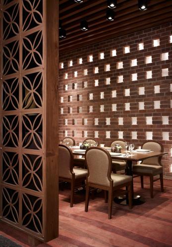 a dining room with tables and chairs and a brick wall at Taj Yeshwantpur Bengaluru in Bengaluru